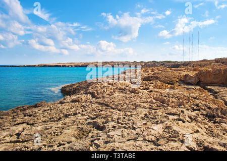 Aussicht auf die Blaue Lagune in der Nähe von Kap Greco, Zypern. Karge Felsen Küste in der Nähe von tiefen azurblauem Wasser. Warmer Tag im Herbst Stockfoto