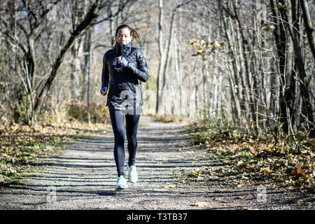 Frau läuft auf unbefestigten Weg im Herbst Stockfoto