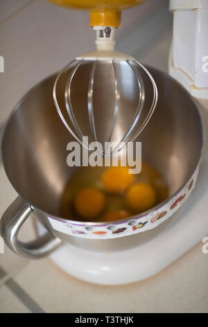 Küche front mit Planetengetriebe Mixer mit Eiweiß und Eigelb in einer Schüssel aus Metall warten gerührt werden. Elektrische Küchenutensilien ustensil verwendet vorzubereiten Stockfoto