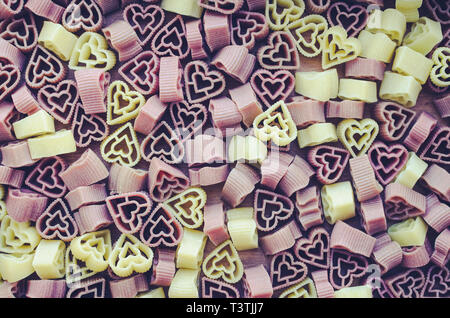 Pasta in Herzform Muster Textur Hintergrund. Herz-förmigen farbigen italienischen Pasta. Kochen mit Liebe. Valentinstag Hintergrund. Ansicht von oben. Stockfoto