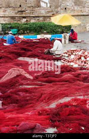 Fishermens ihre Netze flicken im Hafen von Essaouira, Marokko Stockfoto
