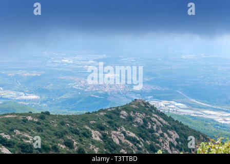 Hazy ungewöhnliche Berge mit grünen Bäumen und bewölkter Himmel in der Nähe von Kloster Montserrat, Spanien. Katalonien Stockfoto