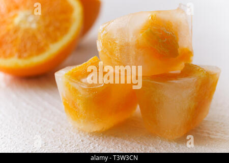 In der Nähe von kleinen Stücke von Orange Frucht gefroren in Eiswürfel auf weißem Hintergrund Stockfoto