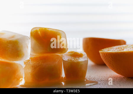 In der Nähe von kleinen Stücke von Orange Frucht gefroren in Eiswürfel auf weißem Hintergrund Stockfoto