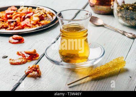 Kräutertee in der orientalischen Glas mit arabischen Mutter Genüsse auf Metallplatte über Licht Holz- Oberfläche Stockfoto
