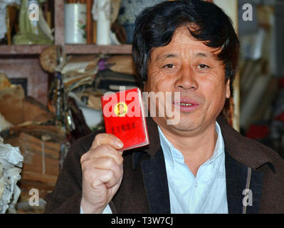 Im mittleren Alter Chinesischer Mann mit gefärbte schwarze Haare Wellen seine Kopie von Maos kleine rote Buch. Stockfoto