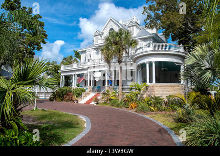 Vintage White Mansion in Key West Florida mit gebogener Ziegelstein Auffahrt und Palmen. Stockfoto