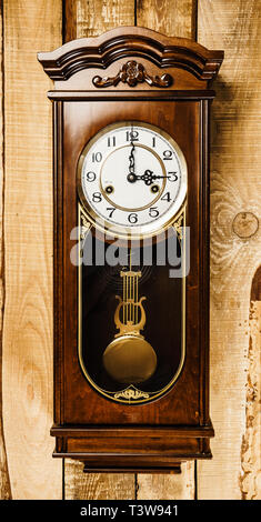 alte und große Uhr an einer Holzwand hängen Stockfoto