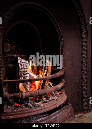 Ein offenes Feuer mit teilweise verbrannte Protokolle in einem viktorianischen Kamin. Stockfoto