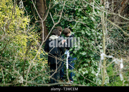 Jungs im Teenageralter bunking aus Schule in bewaldeten Gebiet zu verstecken und Rauch eine gemeinsame. North London. 11.03.2011. Stockfoto