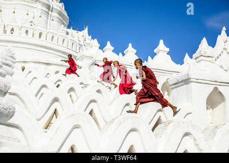 Asiatische Mönche laufen auf weißen Bügelwänden, Hsinbyume Pagode, Mandalay, Sagaing, Myanmar Stockfoto