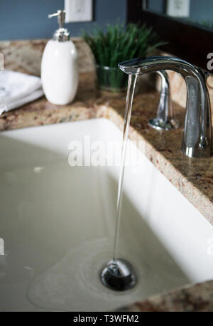 Wasser fließt aus dem Wasserhahn im Waschbecken im modernen Badezimmer Stockfoto