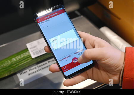 Köln, Deutschland. 10 April 2019, Nordrhein-Westfalen, Köln: eines Kunden Handy scannt die Waren beim Einkaufen in einem Rewe Center. Foto: Henning Kaiser/dpa Quelle: dpa Picture alliance/Alamy leben Nachrichten Stockfoto