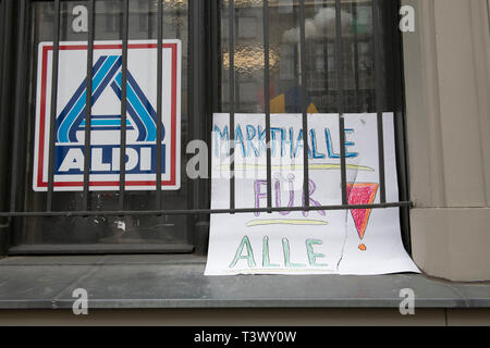 Berlin, Deutschland. 11 Apr, 2019. Ein selbst gemalten Schild mit der Aufschrift 'Markthalle für Alle!" wird von einem Fenster neben ein Aldi-Logo angebracht. Der Aldi in der Markthalle Neun in Kreuzberg ist Weise zu geben. Die Bewohner unerwartet Stand up für seinen Verbleib. (Auf die "falsche Welt im Berliner Öko-Kiez - Kreuzberger Kampf für Aldi) Credit: Paul Zinken/dpa/Alamy leben Nachrichten Stockfoto