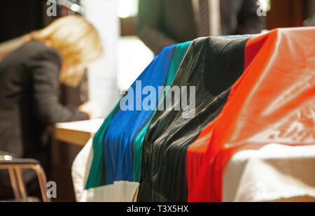 Stuttgart, Deutschland. 12 Apr, 2019. Flaggen der indigenen australischen Stämme liegen auf einer Tabelle oben eine Box. Baden-Württemberg Hände über zehn menschlichen Schädeln nach Australien. Die Schädel der Ureinwohner Australiens hatte in Europa um 1900 für "wissenschaftliche Zwecke" angekommen. Foto: Simon Sachseder/dpa/Alamy leben Nachrichten Stockfoto