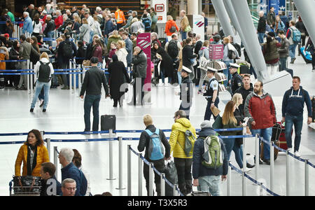 12 April 2019, Nordrhein-Westfalen, Düsseldorf: Fahrgäste stehen vor der Check-in-Schaltern auf der Abflugebene des Flughafens. Am Samstag beginnen die Osterferien in Nordrhein-Westfalen. Foto: David Young/dpa Stockfoto