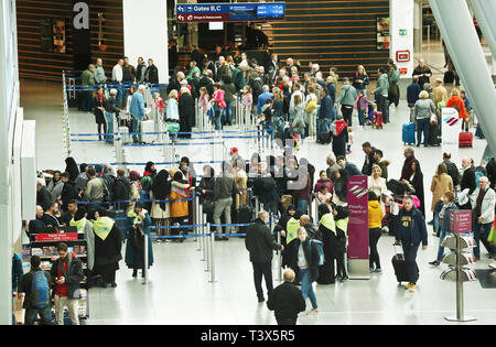 12 April 2019, Nordrhein-Westfalen, Düsseldorf: Fahrgäste stehen vor der Check-in-Schaltern am Ausgang des Flughafens. Am Samstag beginnen die Osterferien in Nordrhein-Westfalen. Foto: David Young/dpa Stockfoto