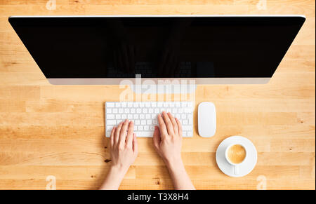 Weibliche Hände arbeiten auf modernen Desktop Computer. Blick von oben auf die hölzernen Schreibtisch mit großen Desktop Computer, weibliche Hände auf der Tastatur, der Maus und c Stockfoto