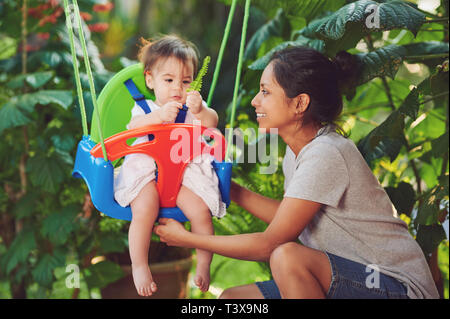 Krankenschwester spielen mit Baby Mädchen hängen auf Schaukeln Stockfoto