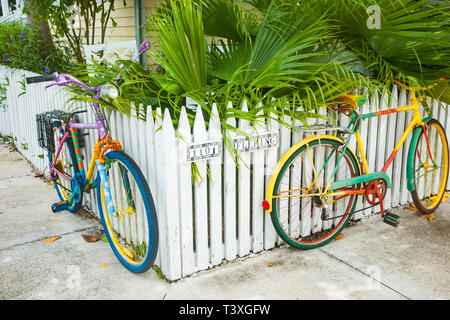 KEY WEST USA - 26. Juni 2012; Zwei mehrfarbige Zyklen zu weißen Lattenzaun, Street Art, die sich in der Ecke. Stockfoto