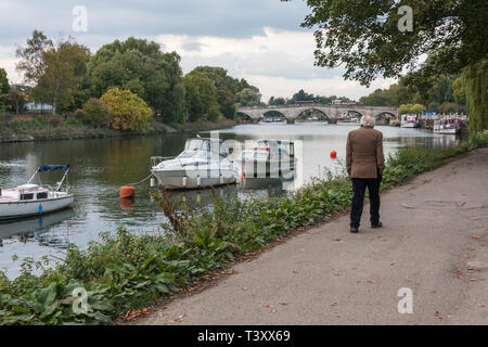 Ein älterer Mann entlang der malerischen Ufer in Richmond upon Thames, Surrey, England bummeln Stockfoto