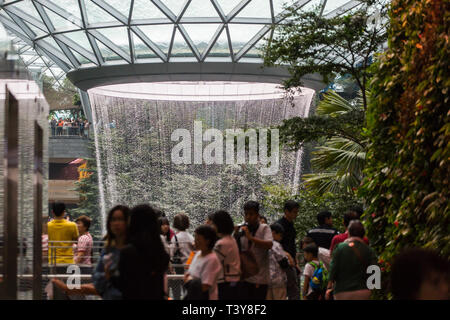 Im Innern des Jewel Changi Airport bestaunen die Menschen den Rain Vortex, den höchsten Indoor-Wasserfall der Welt, in Singapur. Stockfoto