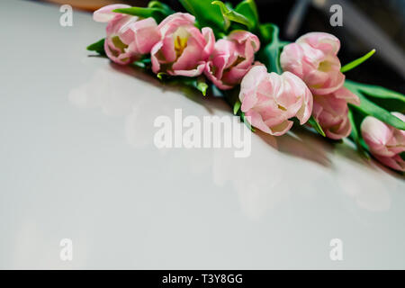 Bündel von rosa Tulpen auf weißer Tisch. Banner mockup Karte mit Kopie Raum für Gratulation, Frau oder Muttertag, Ostern, Frühling Urlaub, Geburtstag Stockfoto