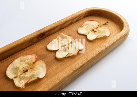 Close-up Teil der Lüge diagonal längliche Holzplatte mit Apple Chips auf weißem Hintergrund. Gesunden Snack. Ansicht von oben. Stockfoto