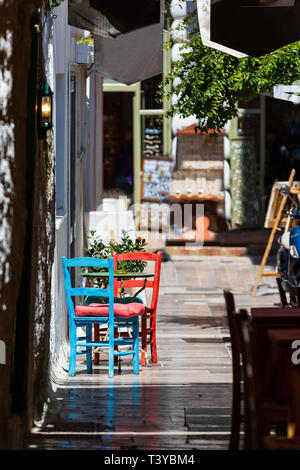 Nafplio, Griechenland Blick auf die Altstadt mit roten und blauen bunten Tisch und Stühlen in kleinen Street Cafe in Nafplion, Peloponnes Stockfoto