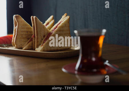 Cheddar und Wurst in Scheiben Toast Gurke tomate Kaffee zum Frühstück vorbereitet Stockfoto