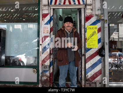 Ein Mann, der vor einem Friseur austeilen Business promotional Cards. Auf Roosevelt Ave. in Jackson Heights, Queens, New York Stockfoto