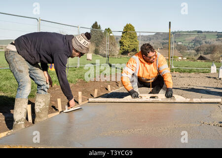 Presteigne, Powys, Wales, UK. Arbeiter mit Beton schwimmt der Oberfläche eines frisch gelegte Betonboden zu glätten Stockfoto