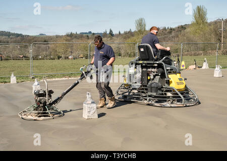 Presteigne, Powys, Wales, UK. Männer mit macht Kellen (power Floats) die Oberfläche eines frisch gelegte Betonplatte Stock zu glätten Stockfoto