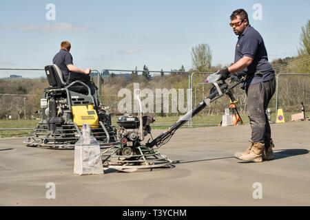 Presteigne, Powys, Wales, UK. Männer mit macht Kellen (power Floats) die Oberfläche eines frisch gelegte Betonplatte Stock zu glätten Stockfoto