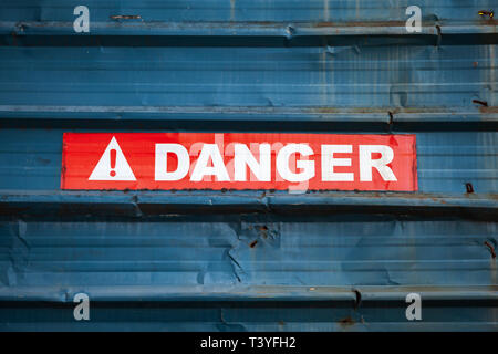 Warnschild auf dem roten Klebeband über grungy blau Metall Wand, close-up Stockfoto