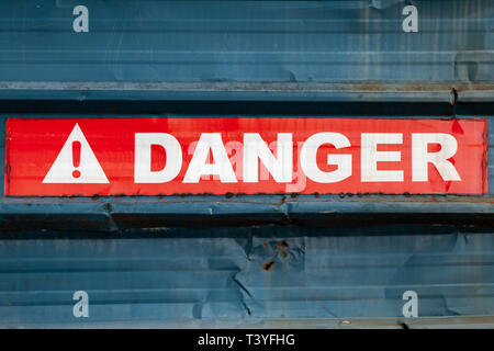 Warnschild auf dem roten Klebeband über grungy blau Metall Wand, bis schließen Foto Stockfoto