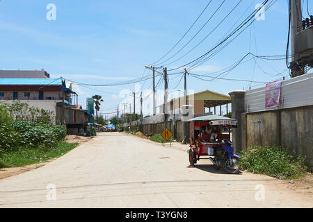 Ein Treiber liegt unter dem Dach seines remorque (kambodschanisches Tuk-Tuk von einem Motorrad gezogen) auf der Straße am Stadtrand von Phnom Penh, Kambodscha. Stockfoto