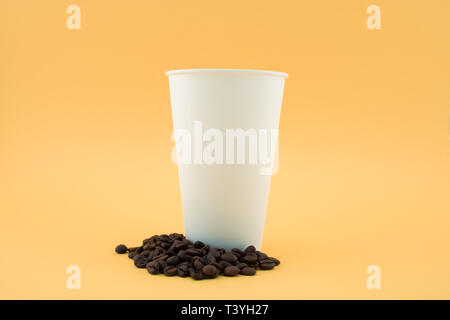 Take-out Tasse Kaffee auf Kaffeebohnen, gelben Hintergrund. Die Tasse ist offen, ohne Deckel. Stockfoto