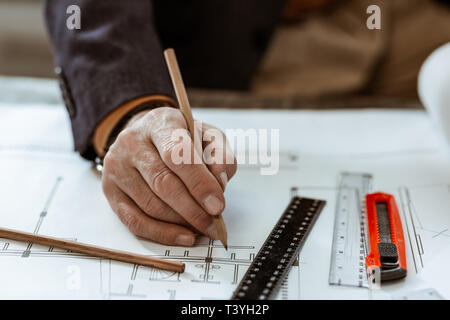 Malerei Entwürfe. Nahaufnahme von Innenarchitekt tragen dunkle Jacke holding Bleistift beim Malen Entwürfe Stockfoto