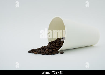 Take-out Kaffeetasse mit dem verschütteten Kaffee Bohnen, weißen Hintergrund. Geröstete Kaffeebohnen. Stockfoto