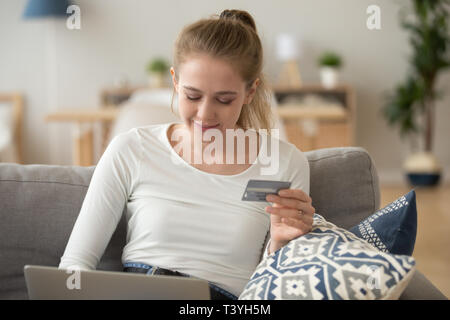 Lächelnde Frau mit Kreditkarte in mit Laptop Hand, Shopping online Stockfoto