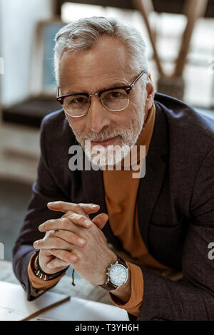 Dark-eyed Designer. Schönen dunklen Augen Innenarchitekt tragen orange Polokragen und dunklen Jacke Stockfoto