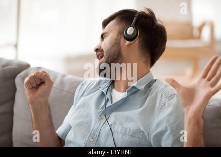 Glückliche Menschen mit Kopfhörern singen Song, stellen sie sich vor das Mikrofon in der Hand Stockfoto