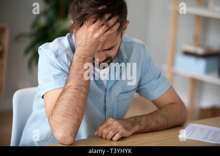 Verärgert frustriert Mann hält den Kopf in den Händen, durch schlechte Nachrichten schockiert Stockfoto