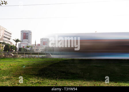 Izmir, Türkei - 10. November 2018: Lange Belichtung Foto von Izmir Straßenbahn auf der Bahn mit Gras. Die Straßenbahn ist Bewegung verwischt. Stockfoto