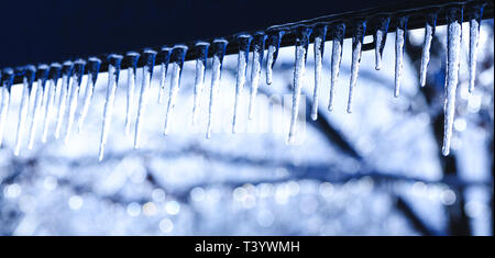 Eiszapfen am schönen hellen Hintergrund. Frühling oder Winter Hintergrund mit Kristall Eiszapfen und fallende glänzend fällt. Eiszapfen mit Wassertropfen hängen von Th Stockfoto