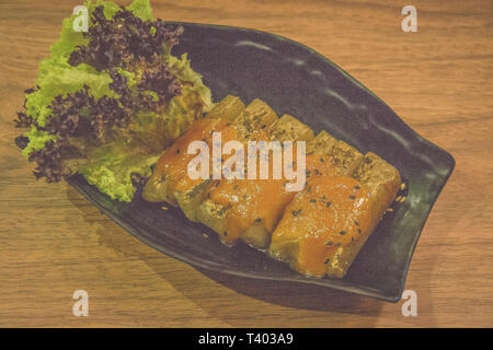 Gegrillte japanische Taro yam Kuchen mit schwarzem Sesam und Kopfsalat Stockfoto