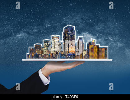 Immobilien, Haustechnik und intelligente Stadt. Geschäftsmann Hand digital Tablet mit Gebäuden Hologramm Stockfoto