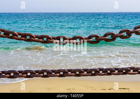 Dicke rostige Ketten mit den Strand, den Sand und das Meer im Hintergrund Stockfoto