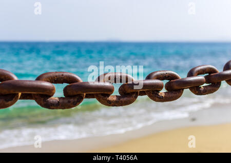 Dicke rostige Ketten mit den Strand, den Sand und das Meer im Hintergrund Stockfoto